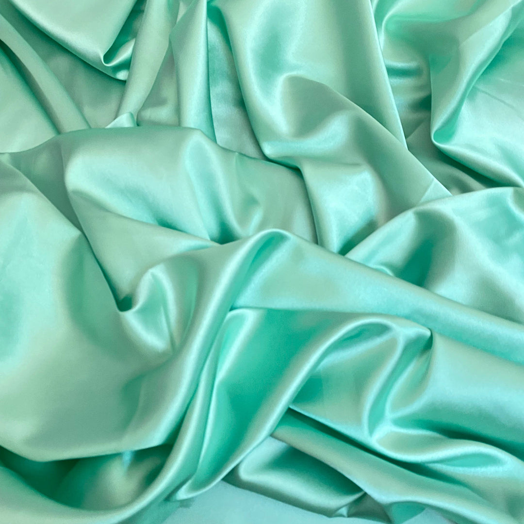 A draped piece of mint green silk charmeuse fabric.