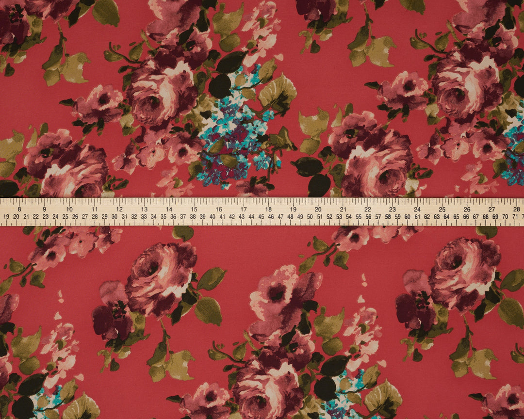 Floral fabric pattern with a ruler at the bottom for scale on a red background