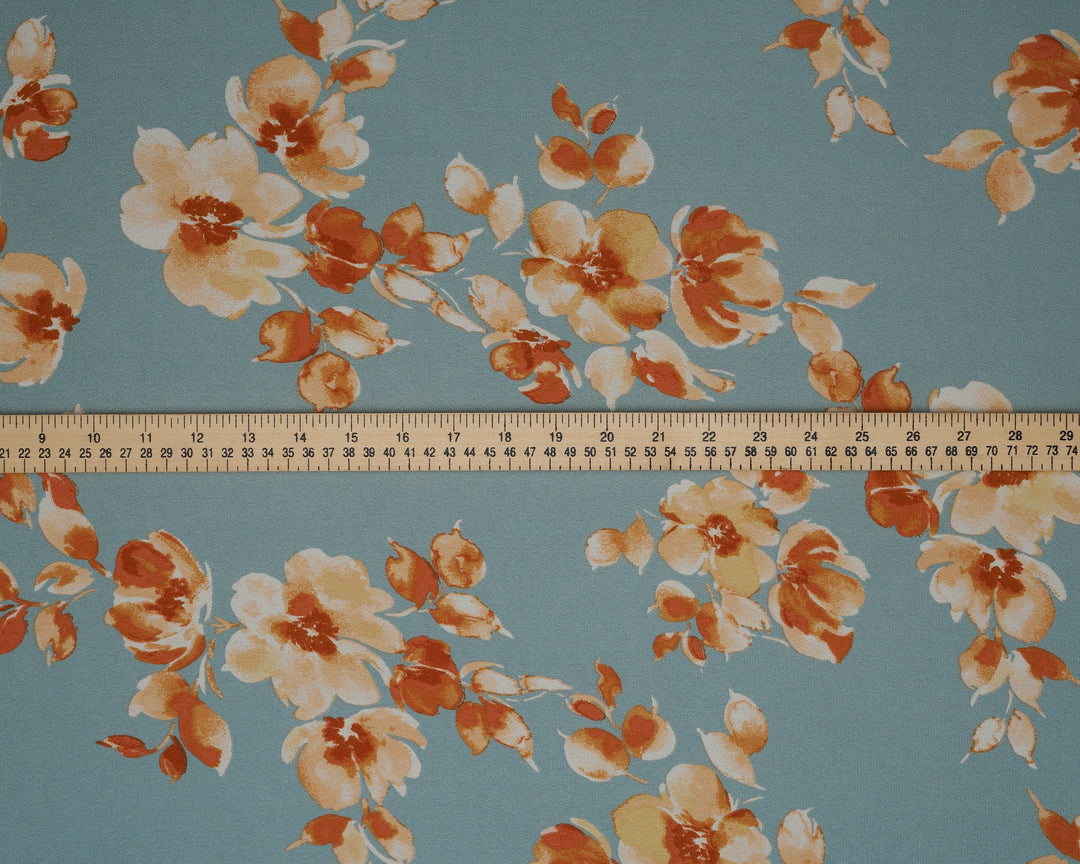 Floral patterned fabric with a ruler at the bottom for scale on a blue background