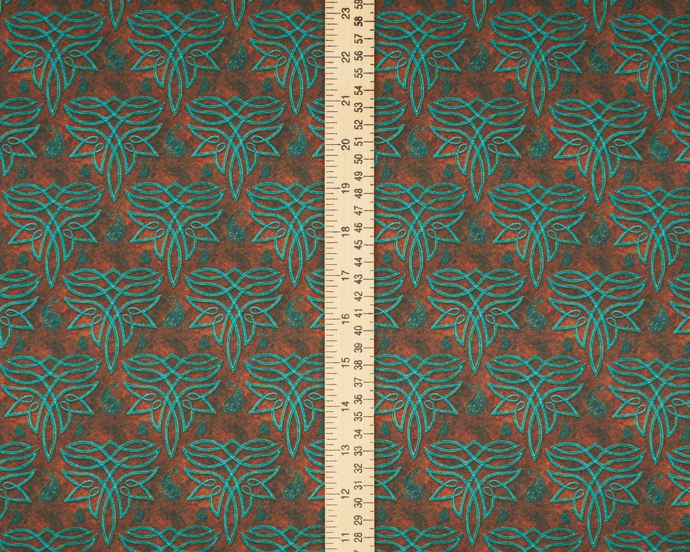 Fabric with a leaf pattern and a ruler for scale on a brown background