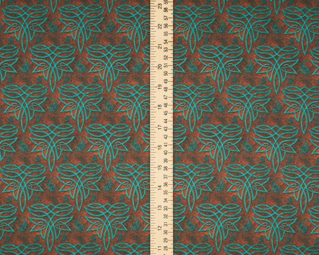Fabric with a leaf pattern and a ruler for scale on a brown background