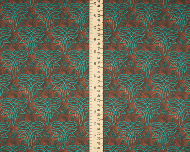 Fabric with a leaf pattern and a ruler for scale on a brown background