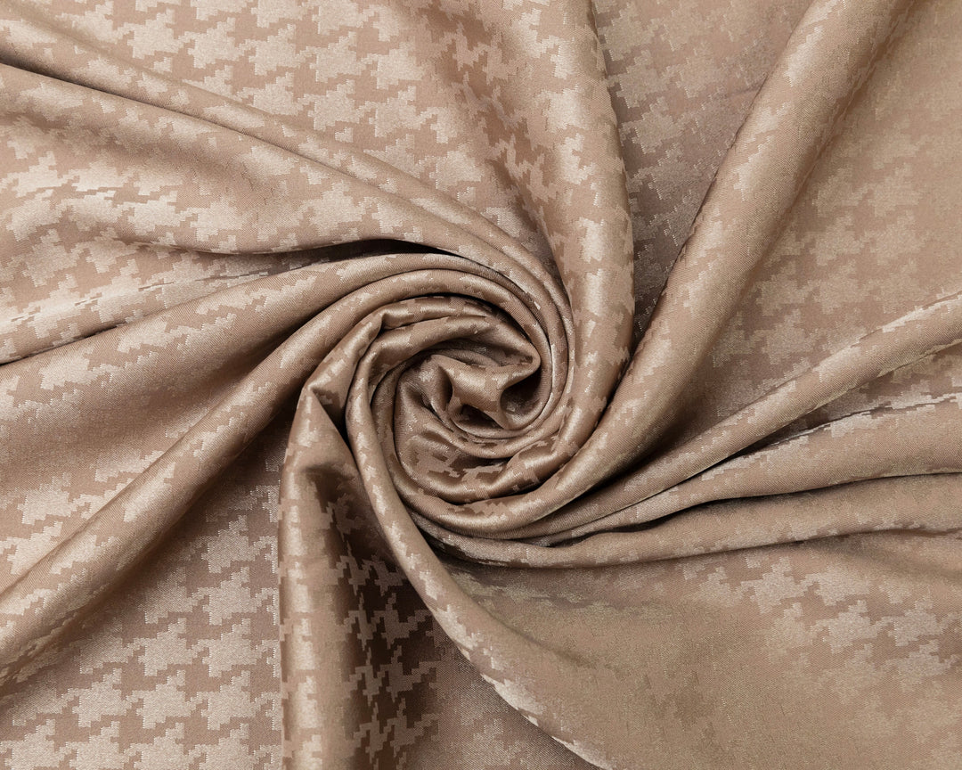 Close-up of beige fabric with a subtle pattern, rolled up.