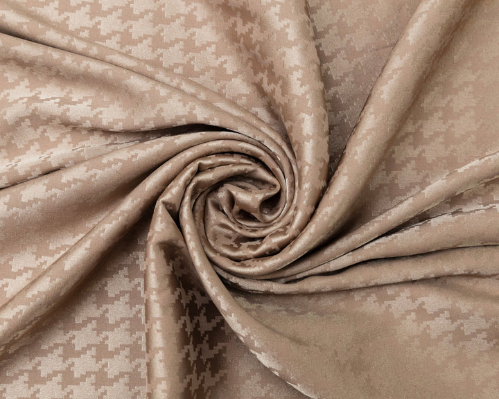 Close-up of beige fabric with a subtle pattern, rolled up.