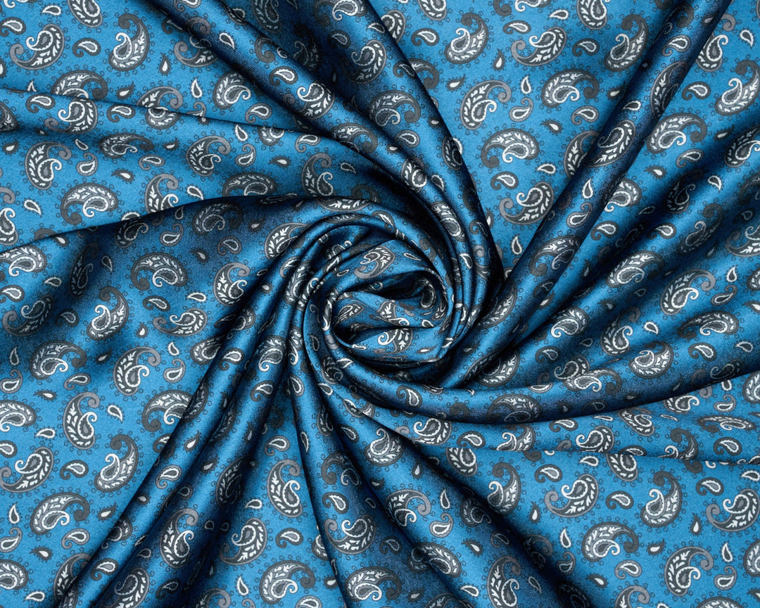 Blue fabric with a white and gray paisley pattern, styled in a spiral drape to show texture and flow.