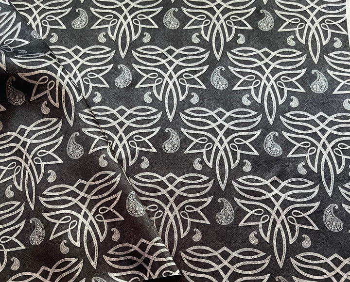 Fabric with white floral pattern on black background draped over a wooden surface